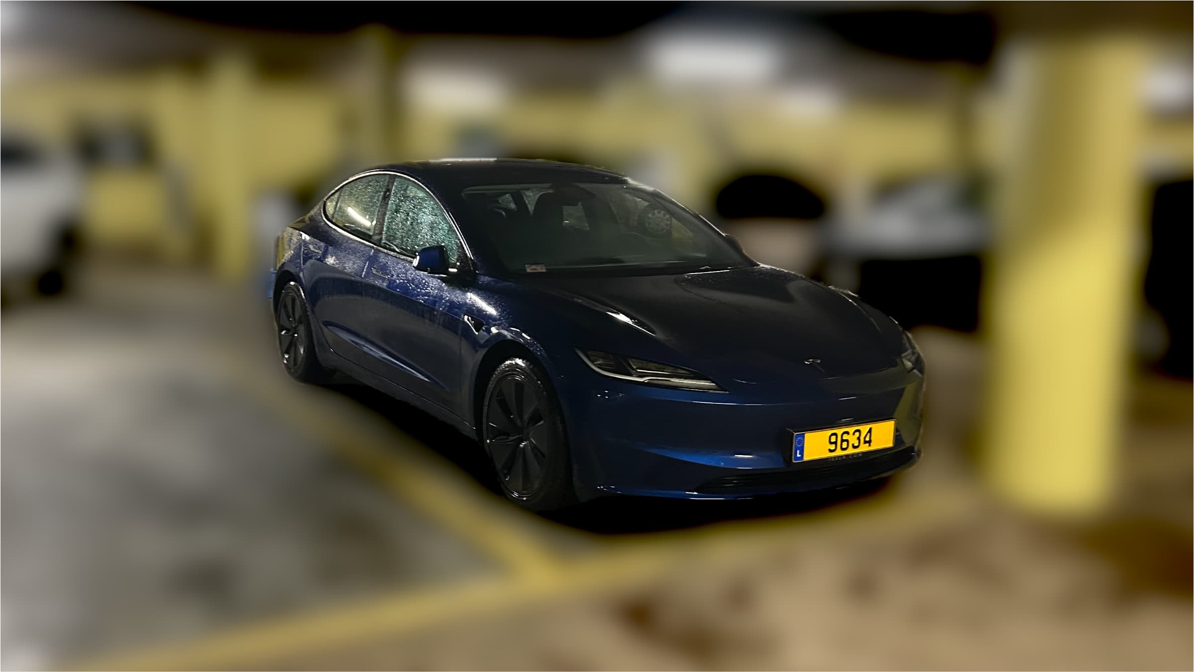 Tesla Model 3 parked in an underground garage under warm lighting